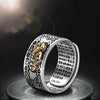 Silver ring featuring a gold pixiu design and detailed coin engravings on a dark background.