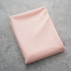 A smooth, pale pink sheer chiffon fabric drape is laid flat on a gray surface.