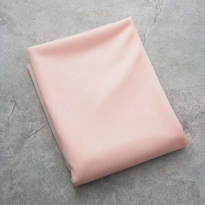 A smooth, pale pink sheer chiffon fabric drape is laid flat on a gray surface.