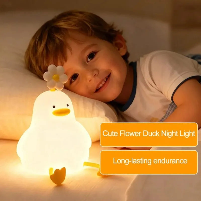A young boy smiles while holding a glowing white flower duck night light.