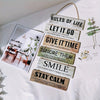 A collection of rustic wooden inspirational hanging signs with text like Rules of Life, Let It Go, and Smile displayed on a w