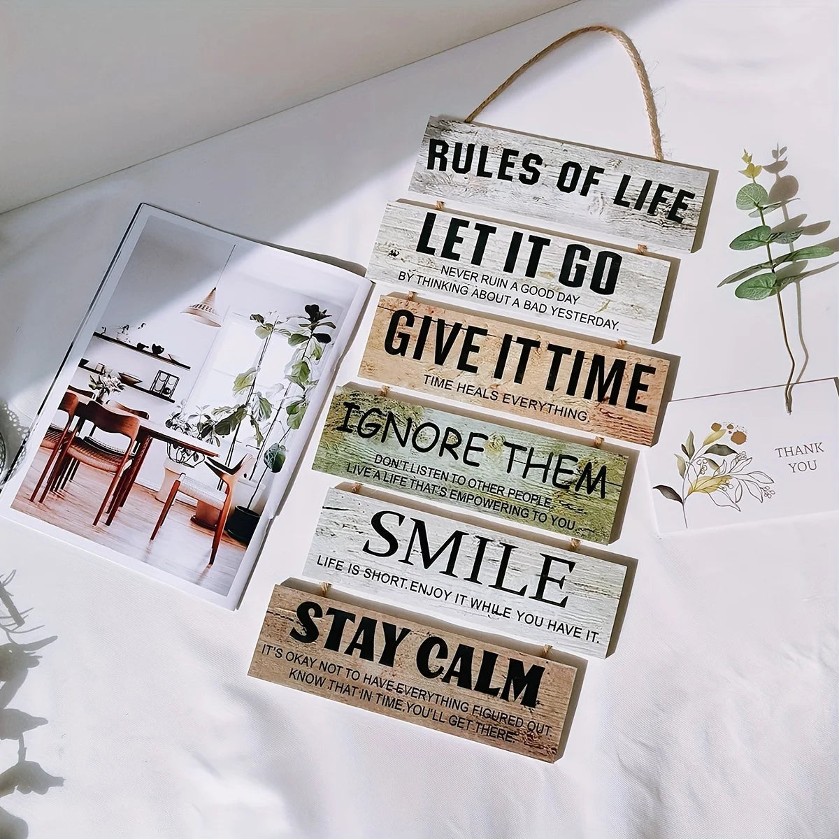 A collection of rustic wooden inspirational hanging signs with text like Rules of Life, Let It Go, and Smile displayed on a w