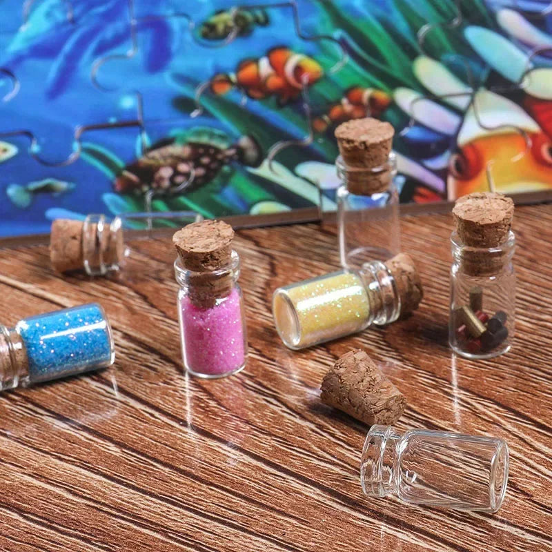 Mini glass bottles with cork stoppers containing colorful glitter and dried botanicals on a wooden surface