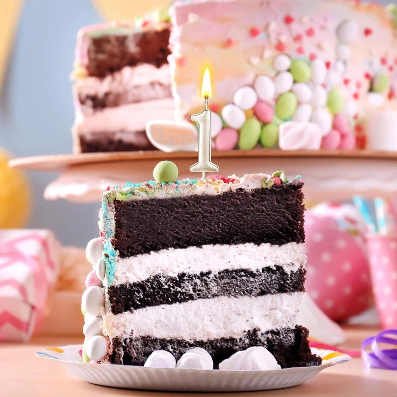 A layered chocolate and white cake decorated with a single candle, set against a blurred background of colorful candies.