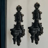 A pair of vintage wrought iron wall-mounted candle holders in black finish.
