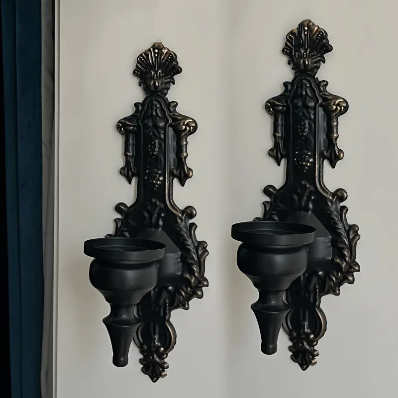 A pair of vintage wrought iron wall-mounted candle holders in black finish.