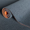 Roll of dark gray artificial grass carpet with an orange accent, showing the texture and coil.