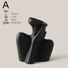 A black ceramic figural vase shaped like an artistic human hand and forearm.