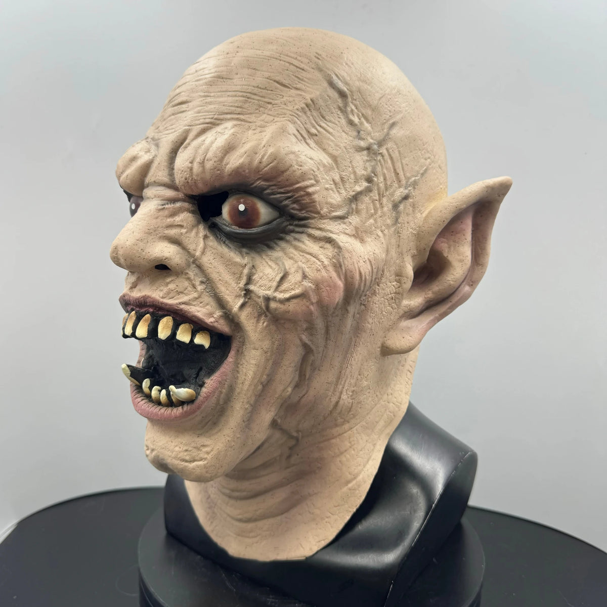 A realistic demon latex mask featuring wrinkled skin and sharp teeth for Halloween