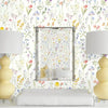 A bathroom setting featuring a mirror framed in metal and surrounded by boho floral peel and stick wallpaper.