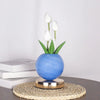 A vase of white tulips in a blue ceramic pot on a woven mat.