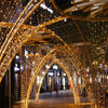 Pasarela arqueada iluminada por luces doradas de hadas cálidas.