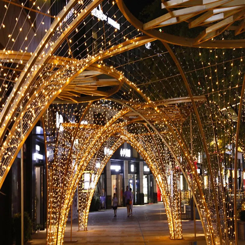 Pasarela arqueada iluminada por luces doradas de hadas cálidas.