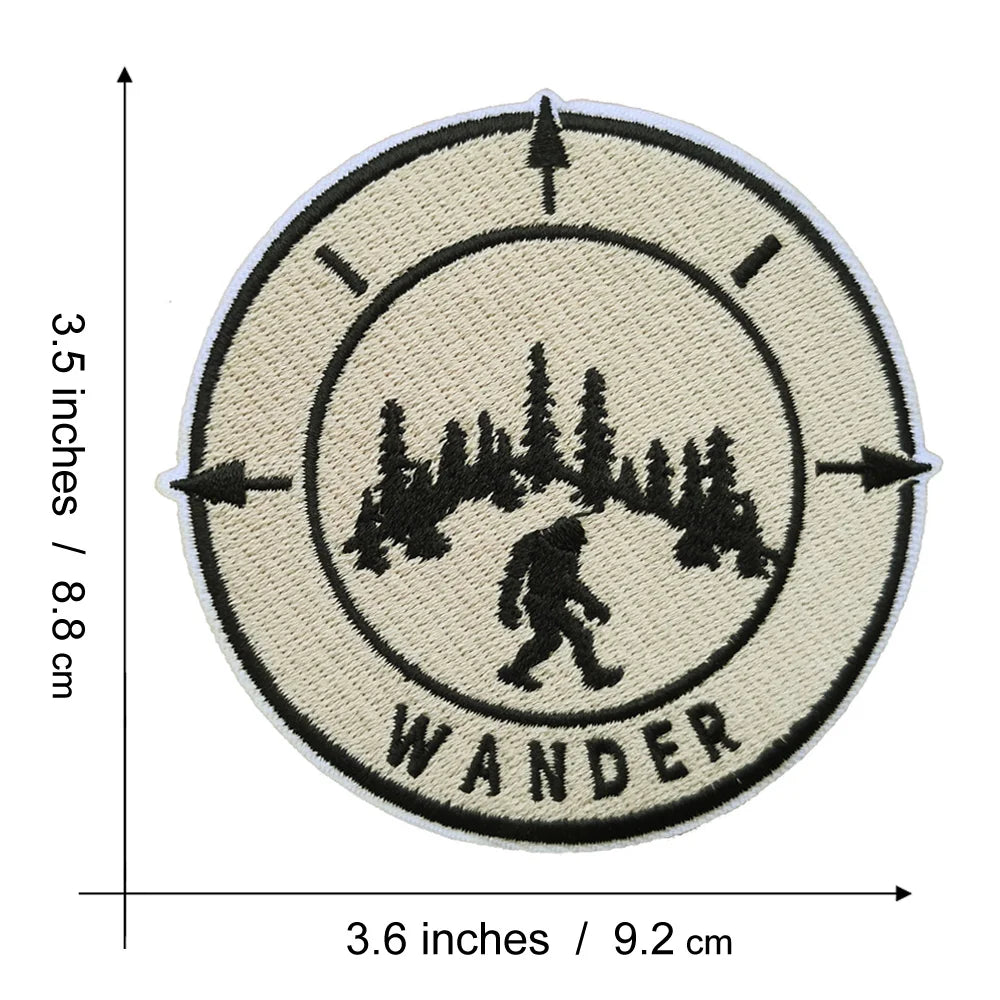 A circular embroidered patch featuring a silhouette of a hiker or wanderer within a forest landscape.