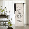 A vertical linen banner with black script text celebrating an engagement for Emma & James, displayed in a clear frame.
