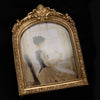 An ornate gold-framed vintage resin photo frame displaying a sepia-toned portrait of a woman.