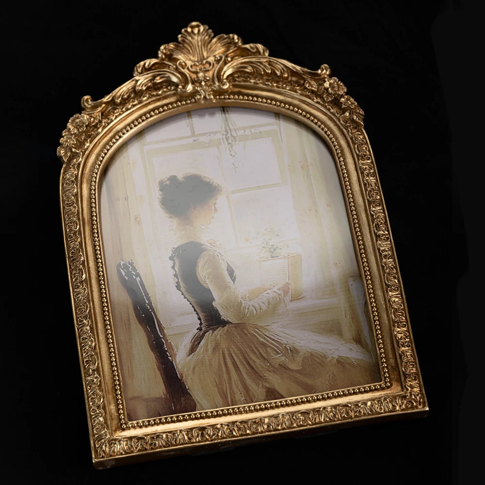 An ornate gold-framed vintage resin photo frame displaying a sepia-toned portrait of a woman.