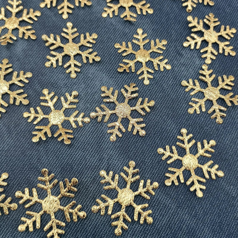 Gold glitter snowflakes scattered across a dark blue fabric background