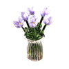 A bouquet of light purple hand-blown glass flowers in a clear glass vase.