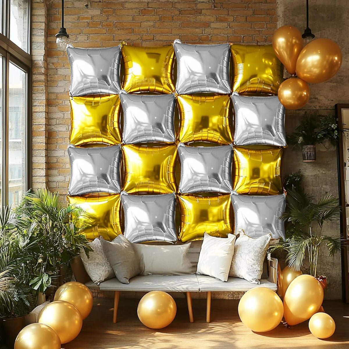 A display of silver and gold foil balloon wall panels arranged in a grid, set against a brick wall with greenery.
