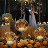 A close-up of a gold-toned hanging lantern with a white candle, set amidst floral arrangements.