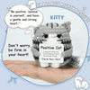 A handmade crochet mini cat plush toy with gray and white stripes is shown resting on a person's hand.