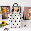 A white canvas tote bag with black polka dots and a black and white checkered handle, displayed on a white surface.