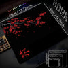 A black gaming mouse pad displaying a red cherry blossom design and size comparisons.