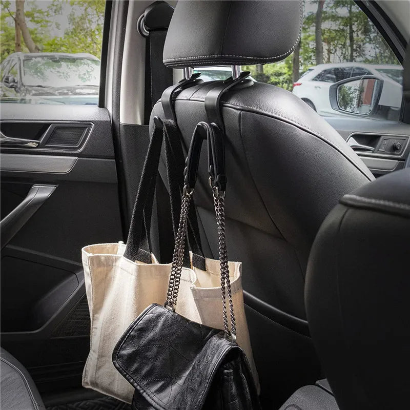 Four black leather headrest hooks with fabric bags are visible inside a car seat.
