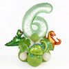 A set of avocado green foil balloons shaped like the number 6 and a dinosaur for birthday decoration