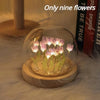A glass cloche containing nine pink and purple LED tulips illuminated on a wooden base.
