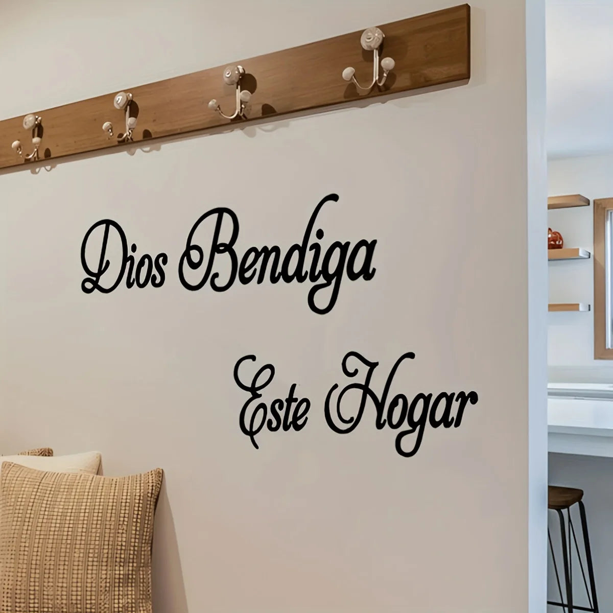 Dekoratives Wanddekal mit dem Text Dios Bendiga Este Hogar an einer weißen Wand über einem Holzpfosten.