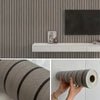 Roll of faux wood grain self-adhesive wallpaper being held by a hand