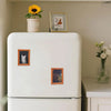 A white fridge magnet featuring a cat smoking, displayed on a kitchen counter.
