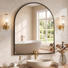A modern bathroom featuring an arched mirror above a white vessel sink and faucet, set against a light beige wall.