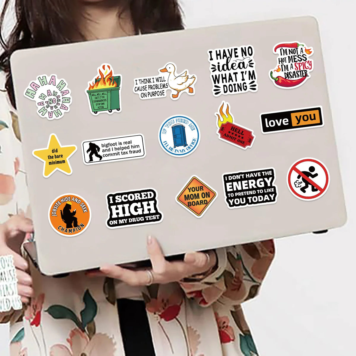 Una mano sostiene una laptop que muestra una colección de pegatinas y stickers de memes de dibujos animados sobre un fondo be