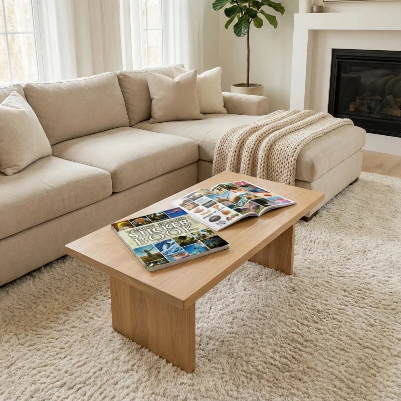A vision board book with inspirational stickers and quotes displayed on a wooden table in a bright living room.