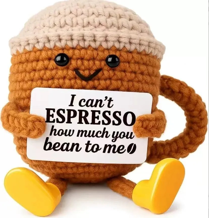 A handmade crochet potato doll made of brown yarn holding a card that reads I can't espresso how much you bean to me