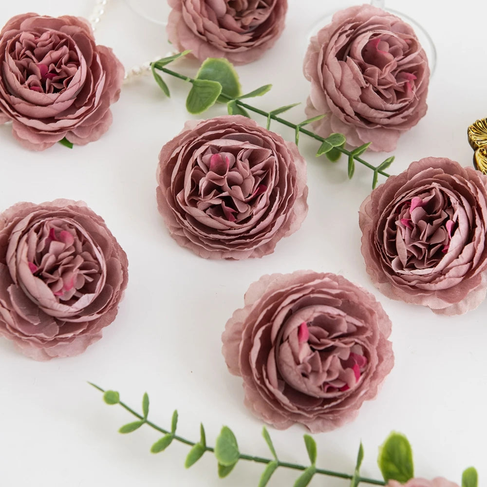 A collection of dusty rose silk peony artificial flowers arranged on a white surface.