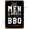 A dark metal sign with white text that reads Real Men Smell Like BBQ and features a grill icon.