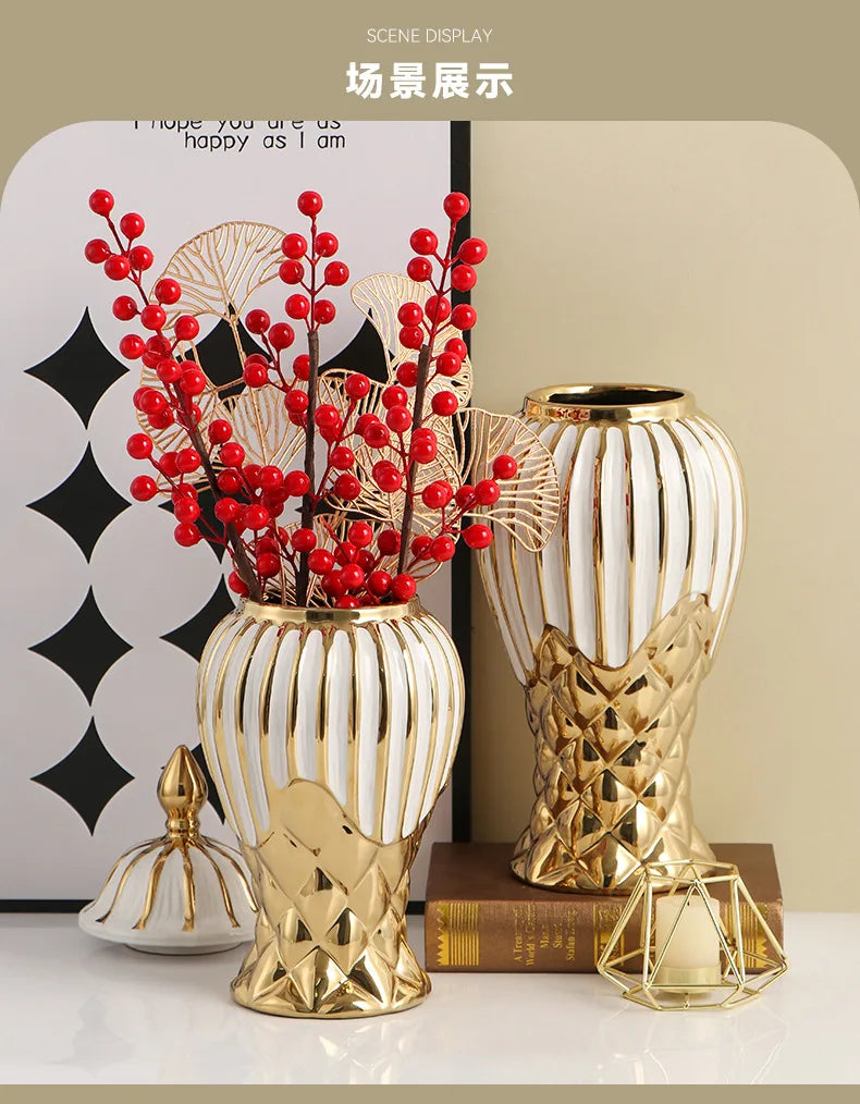 A golden ceramic vase with white stripes holds bright red berries and is displayed next to a gold geometric object.