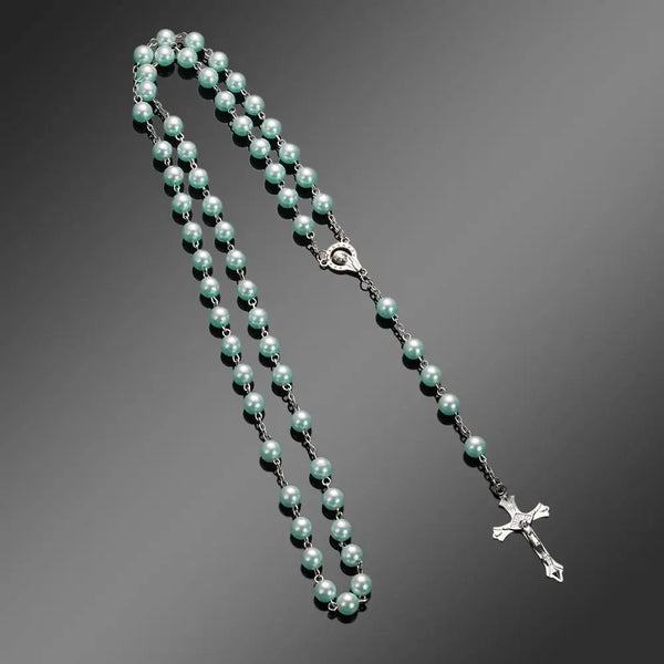 A necklace featuring a vintage cross and Virgin Mary pendant made of small, pale green pearls.