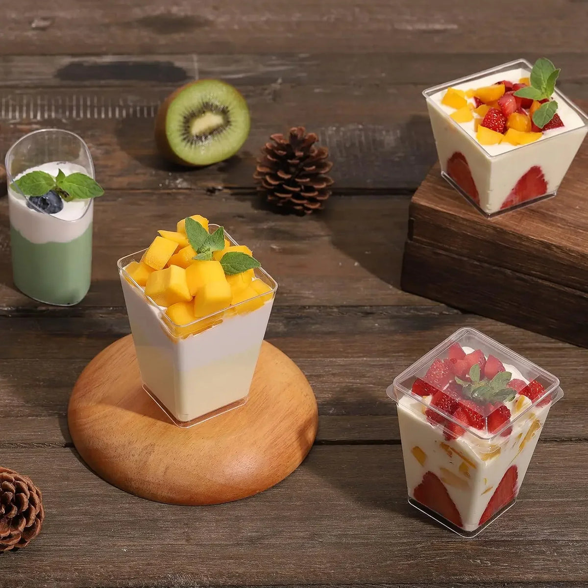 A set of six elegant mini dessert cups filled with layered fruit and cream desserts on a wooden surface.