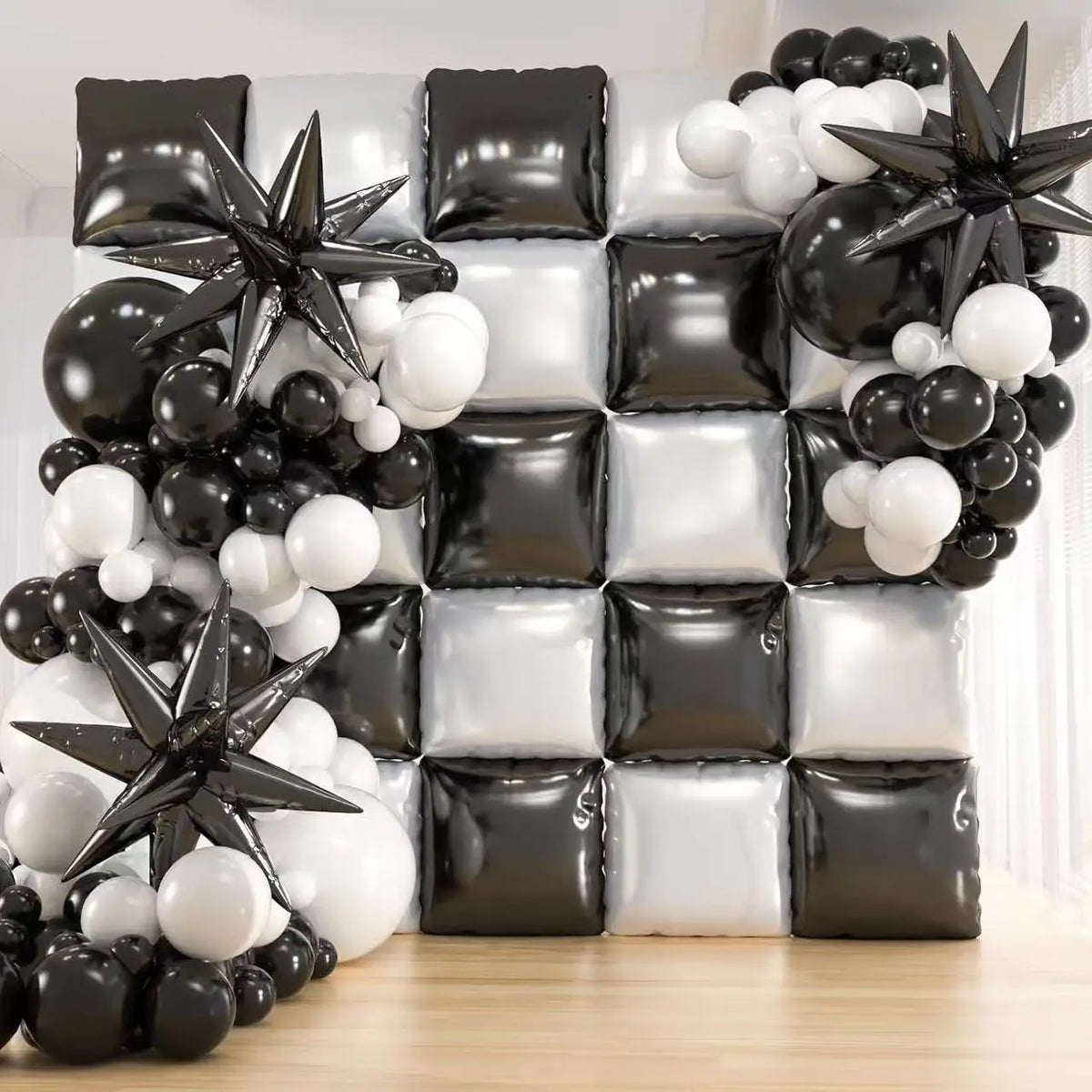 A wall display of black and white square foil balloons and star-shaped decorations for celebrations