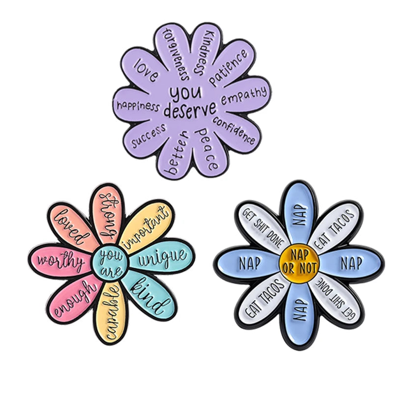 A set of enamel pins featuring a daisy flower design with various positive affirmations like love kindness patience empathy c