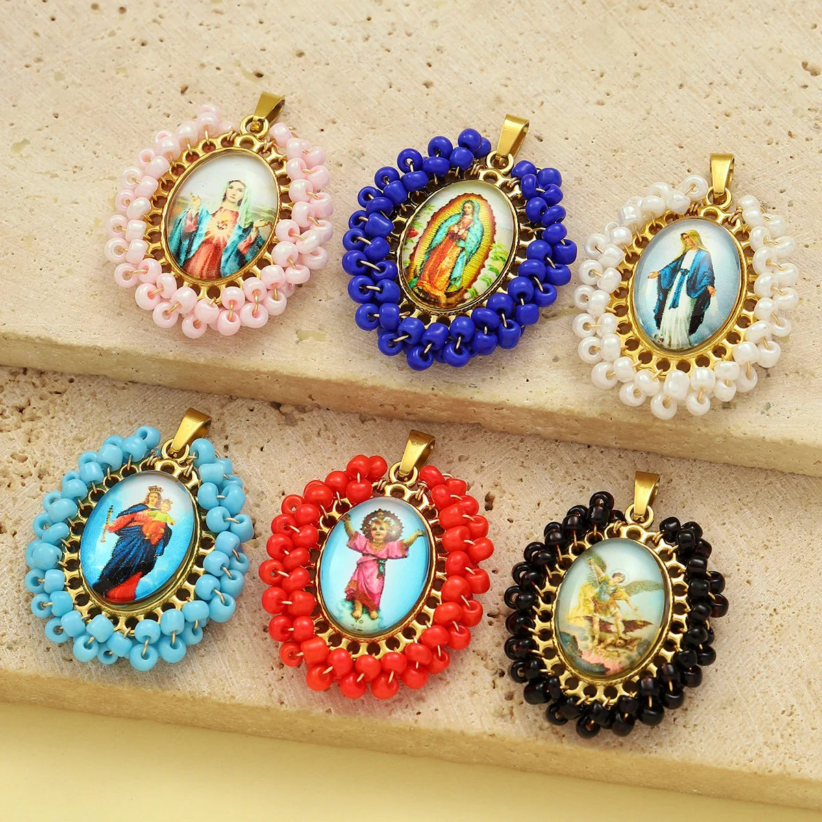 A set of four French stainless steel Virgin Mary charm pendants in various colors including pink, blue, white, and red.