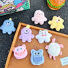 A collection of fuzzy plush monster keychains in various pastel colors like pink purple blue and yellow displayed on a wooden
