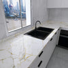 A modern kitchen countertop with a black sink and white marble pattern, featuring a large window view of a city skyline.