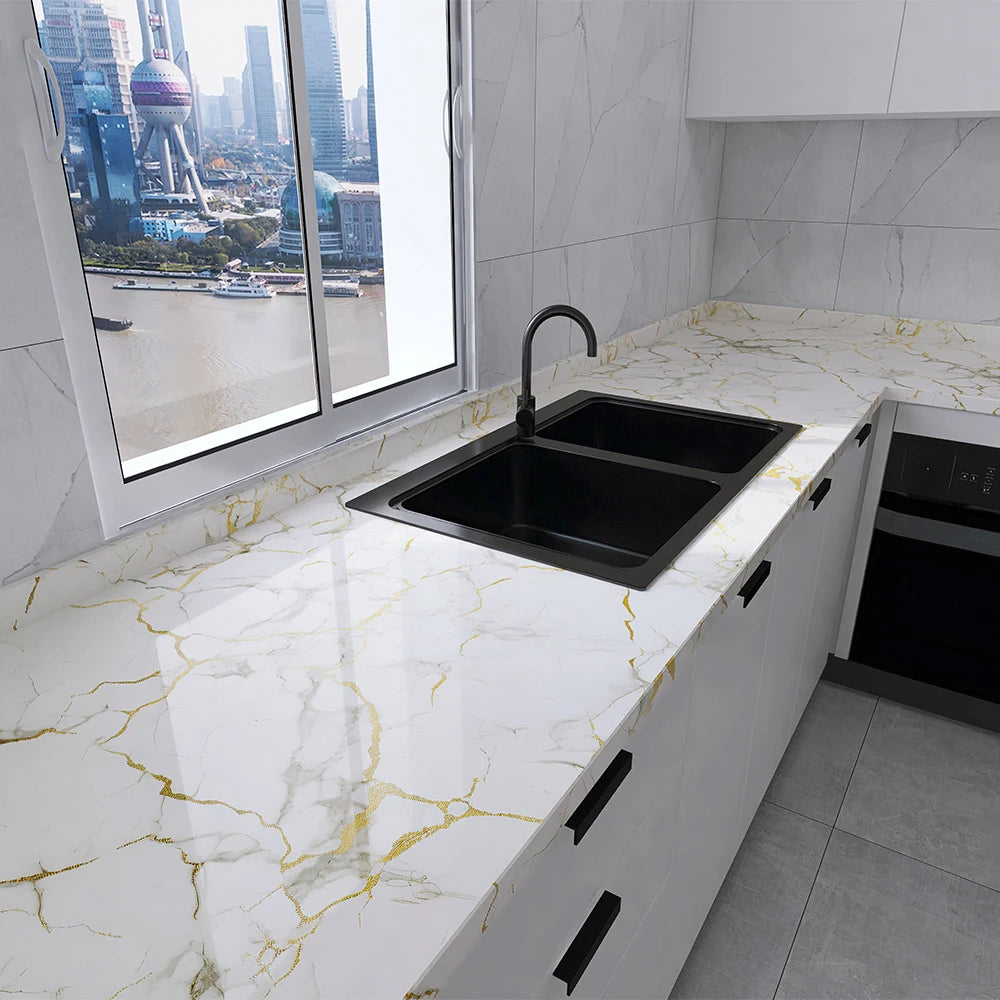 A modern kitchen countertop with a black sink and white marble pattern, featuring a large window view of a city skyline.