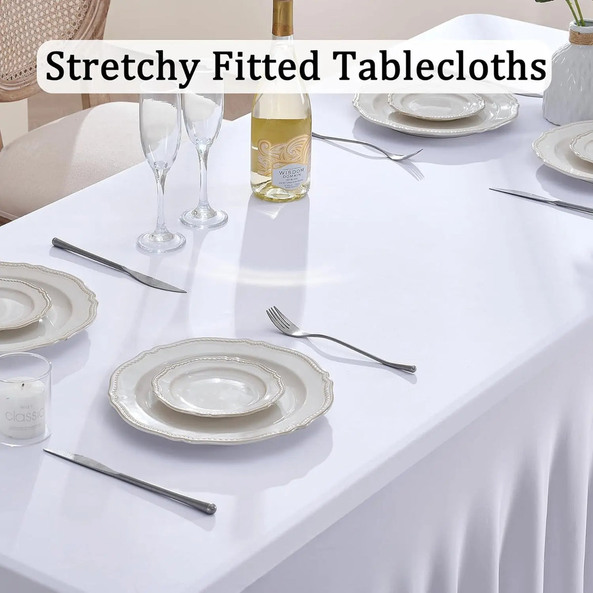 White table setting with a white stretched tablecloth featuring plates, silverware, and a bottle of olive oil.